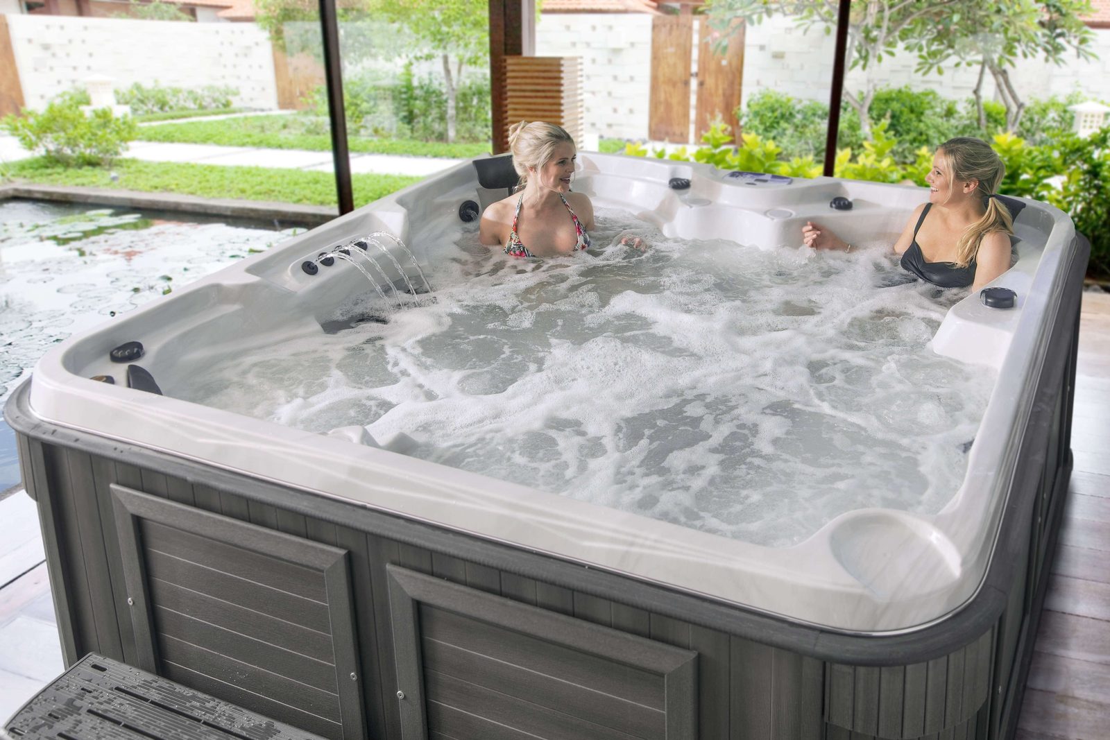 Deux femmes dans un spa Arctic Spas à cabinet gris, dans un jardin